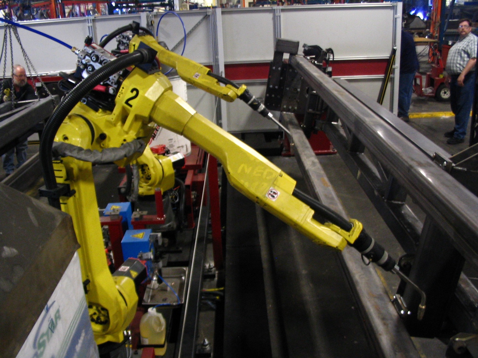 An industrial welding robot on a manufacturing line — real hardware our simulation-trained policies deploy to.